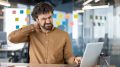 Office worker experiencing neck pain at his desk