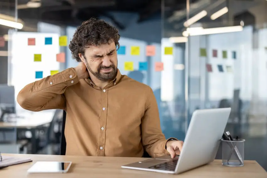 Office worker experiencing neck pain at his desk